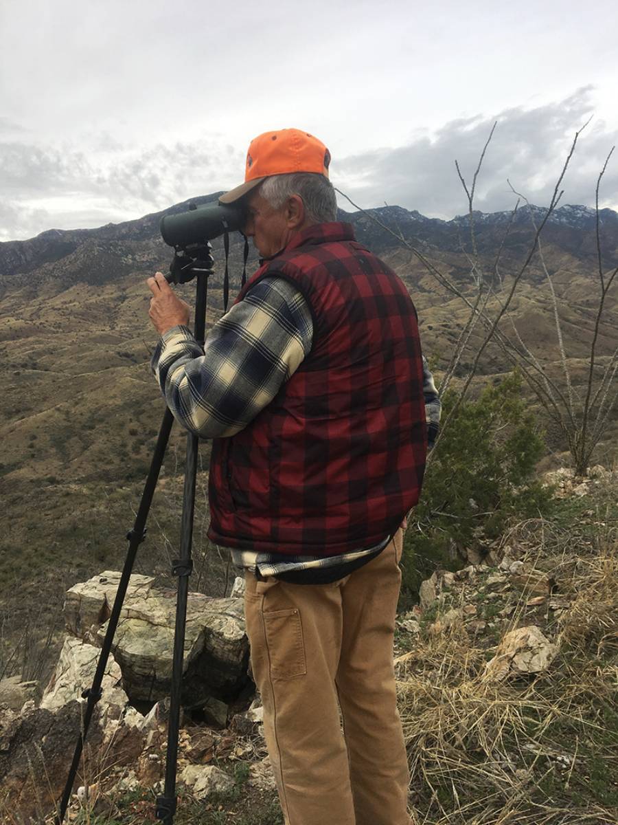 Duwane Adams stands behind his tripod-mounted binocular glassing for trophy deer in southern Arizona. He frequently finds bucks more than a mile away.